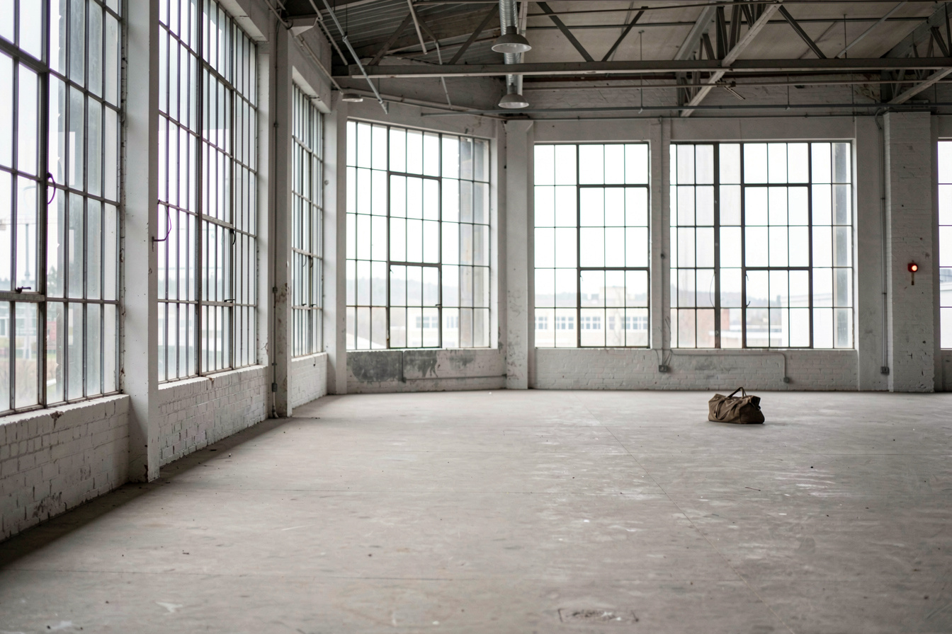 Een trainingszaal met hoge industriële ramen en een lege vloer